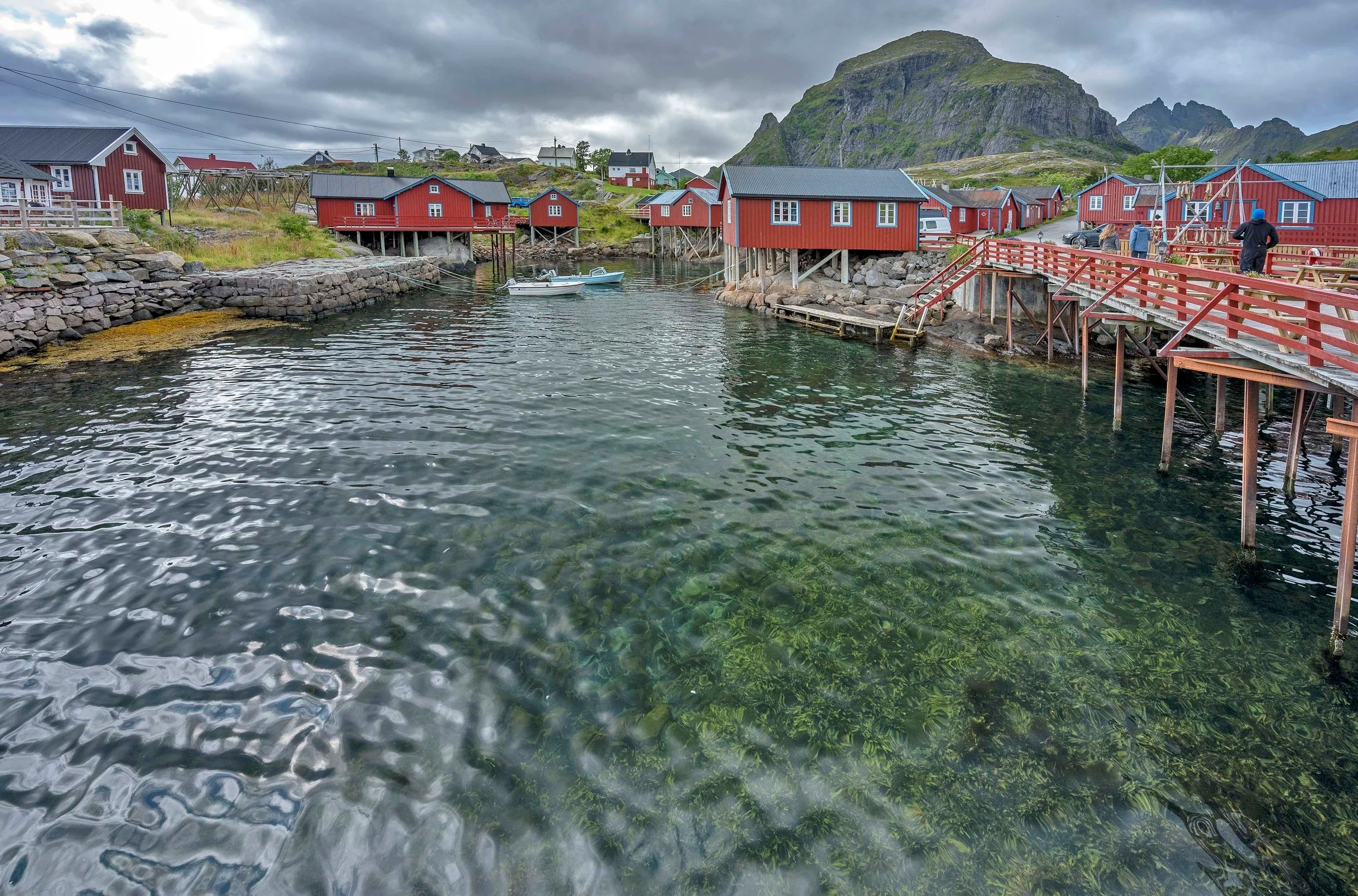 Small village with red houses by a body of water on a cloudy day