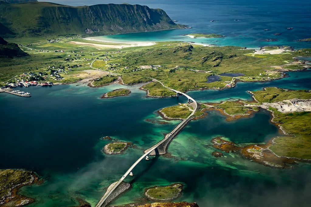Aerial view of a coastal landscape with a bridge connecting islands, surrounded by blue waters.