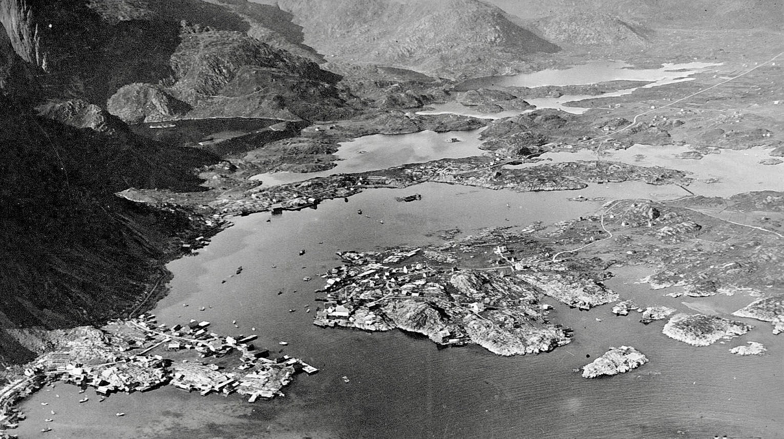 Black and white aerial view of a river landscape with rocky banks and distant mountains.
