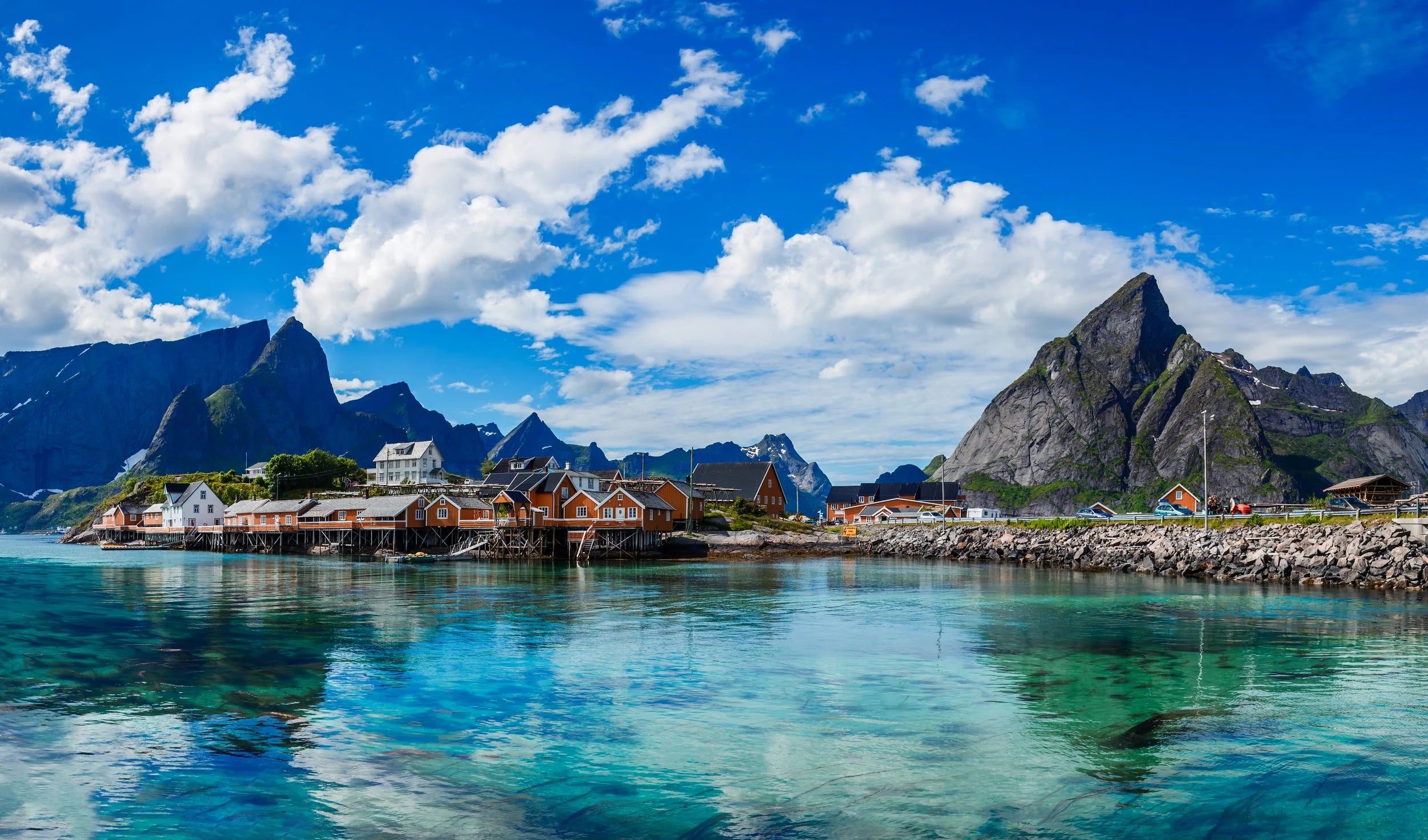 Scenic view of a coastal town with mountains and clear blue water