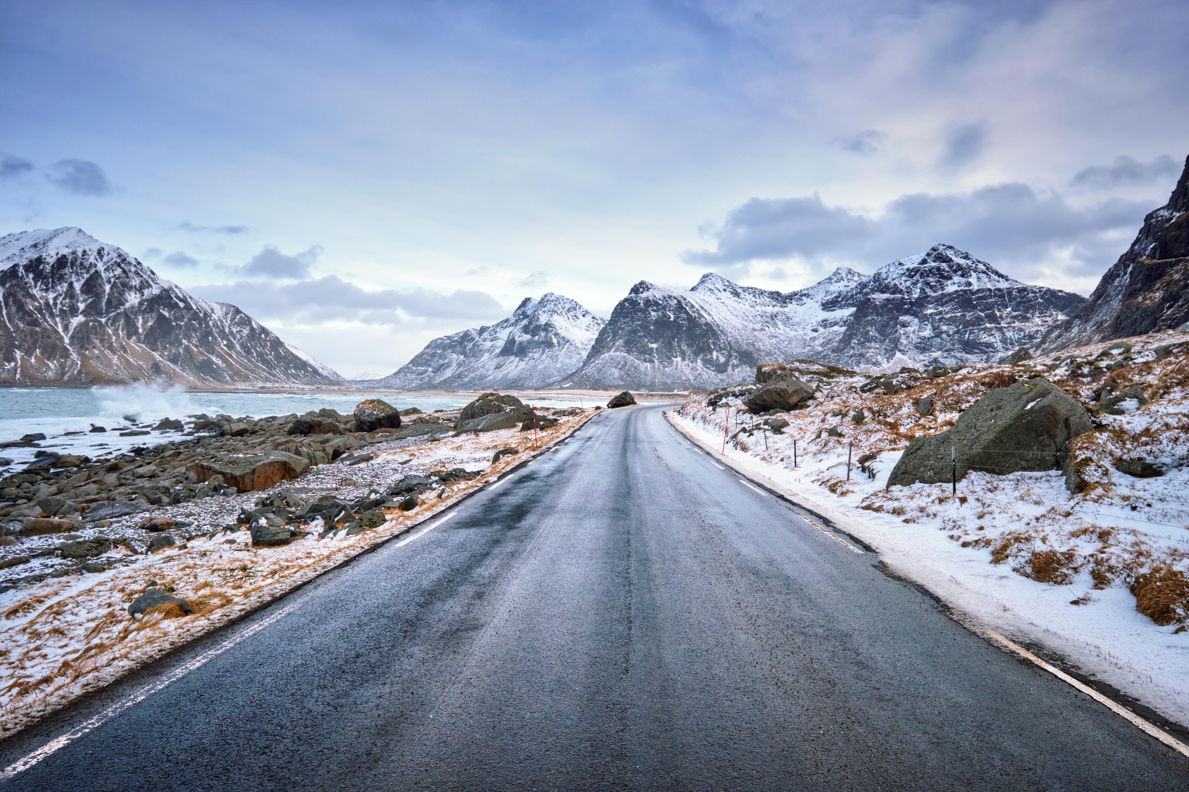 Road leading towards snow-covered mountains under a cloudy sky