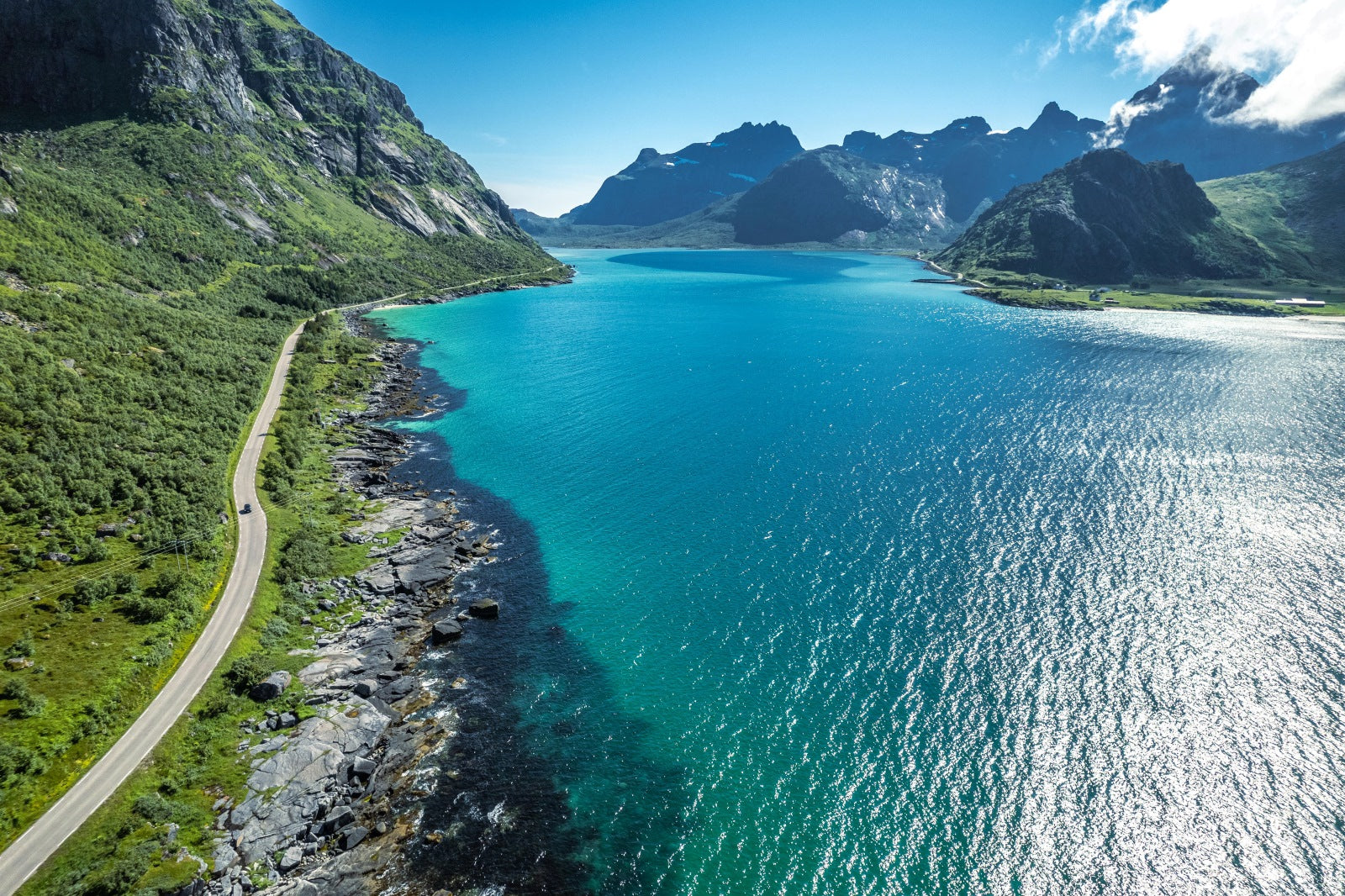 Scenic view of a turquoise lake surrounded by mountains and a winding road.