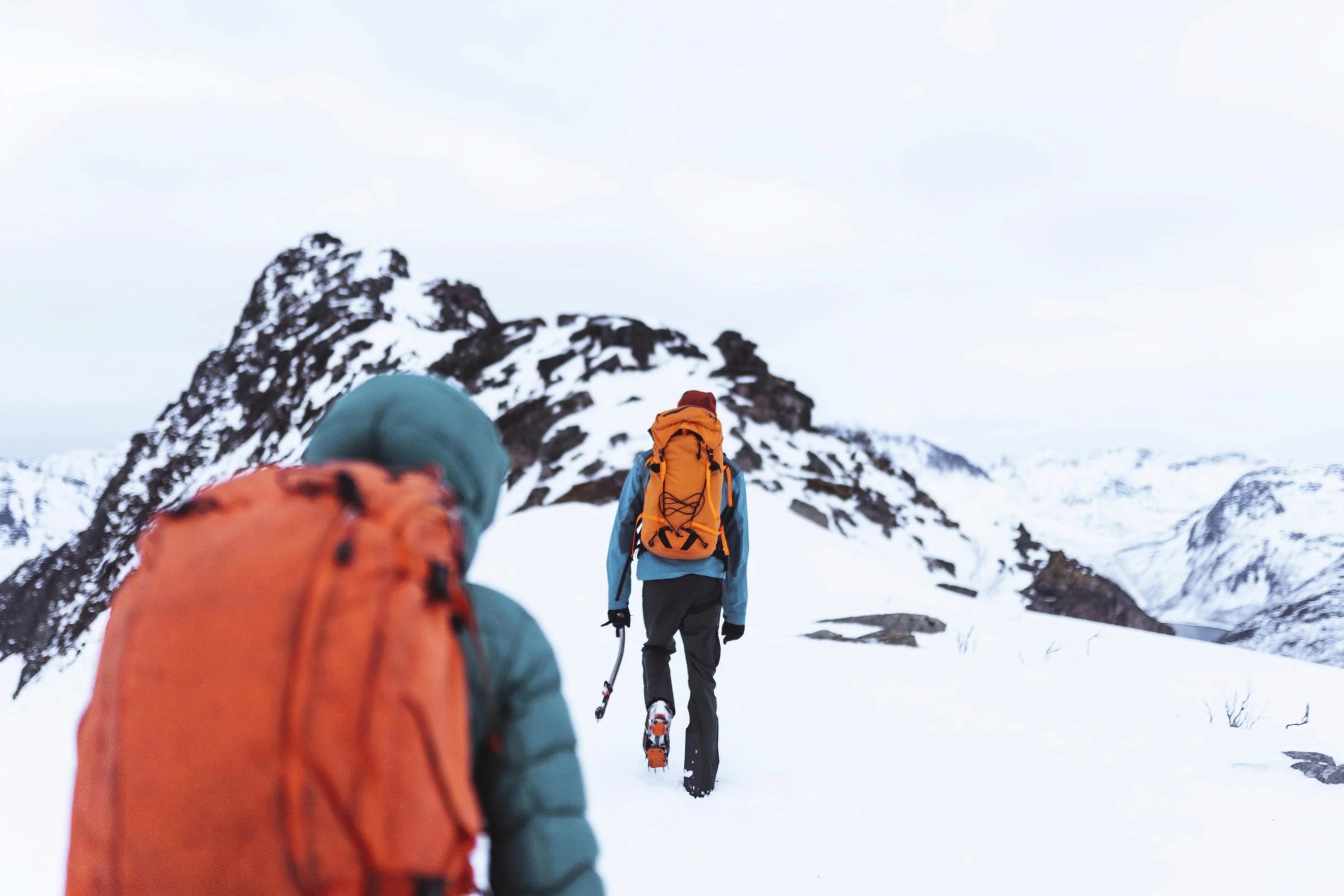 Two hikers with backpacks walking on a snow-covered mountain