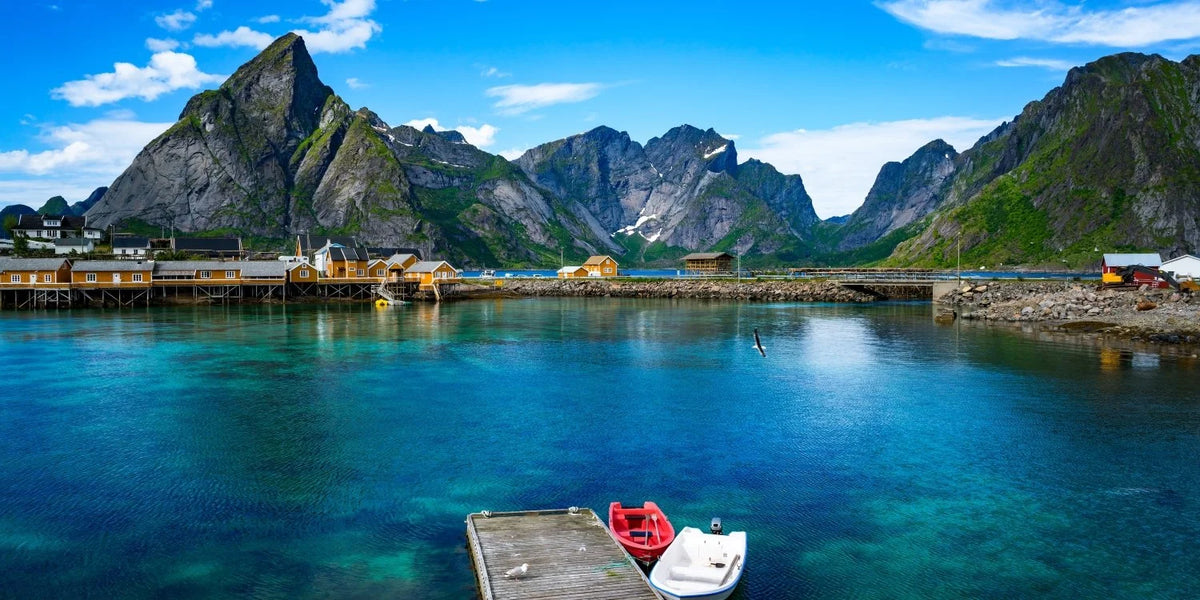 Scenic view of a fjord with mountains, boats, and a dock.