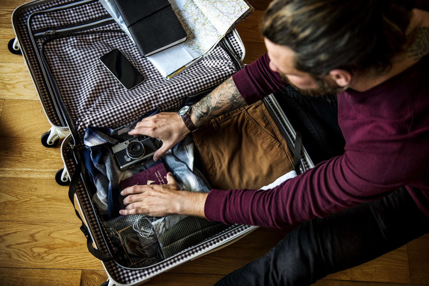 Man packing a suitcase on a wooden floor