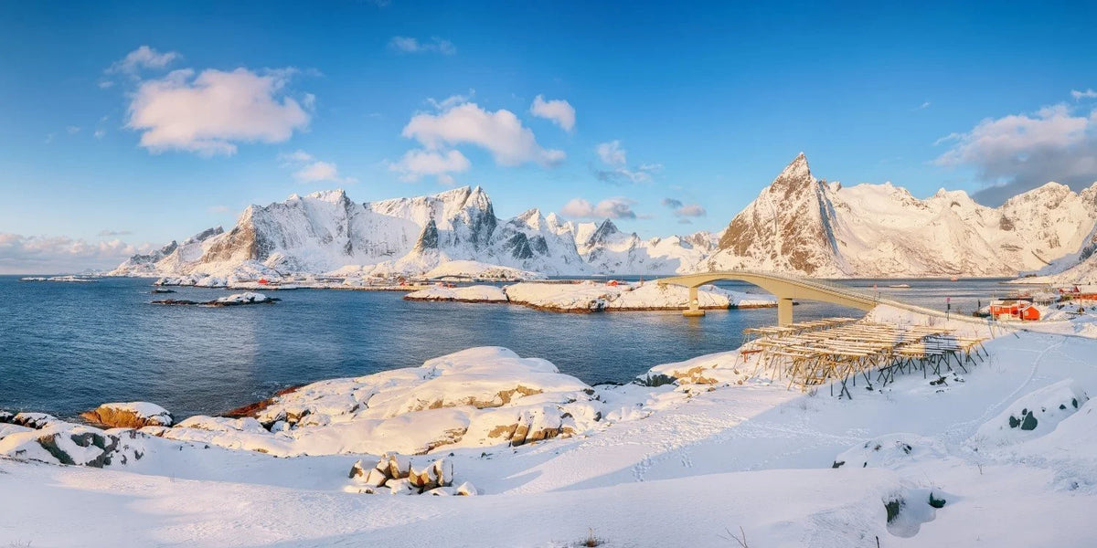 Snowy landscape with a bridge over water and mountains in the background