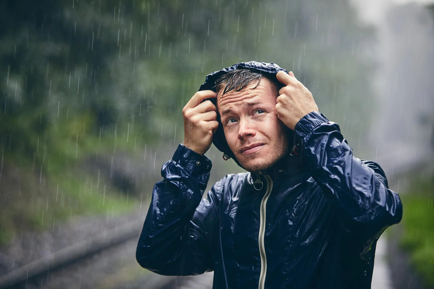 Man in a raincoat adjusting his hood on a rainy day